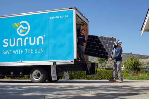 Sunrun solar installers unloading a solar panel from the back of a Sunrun truck