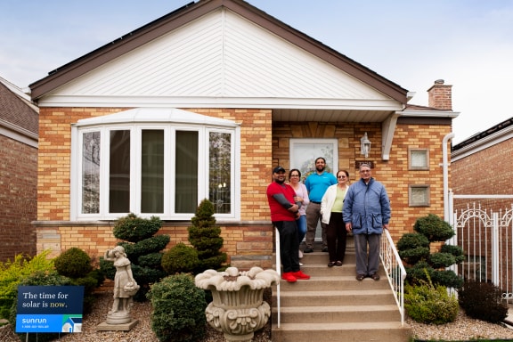 Family on porch in front of house with Sunrun yard sign