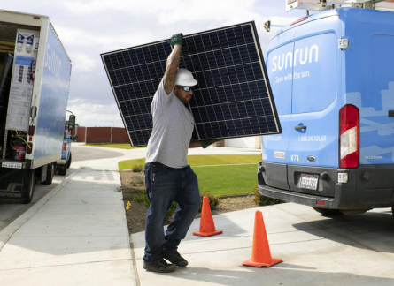 Sunrun solar installer carrying a solar panel.