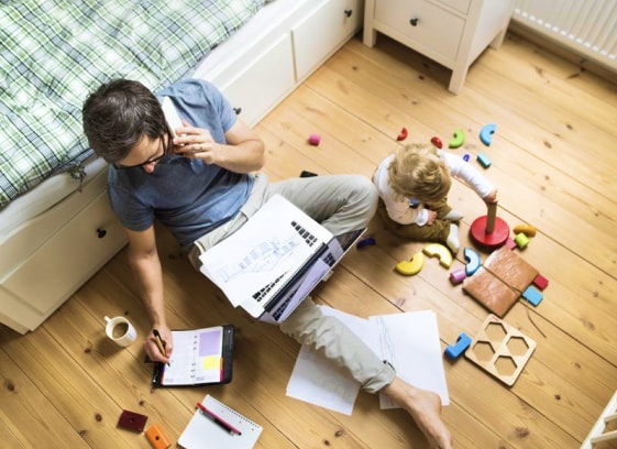 man sitting on floor with son looking over documents