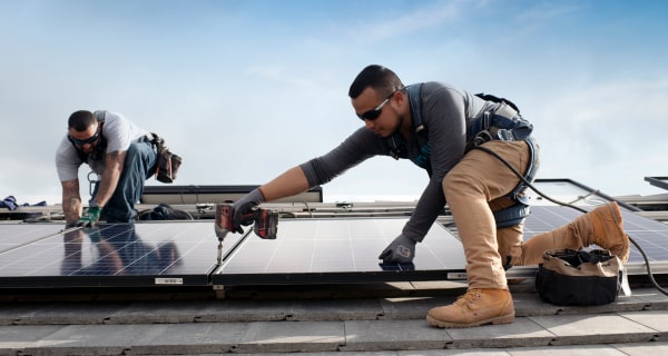 two solar installers install solar panels on roof